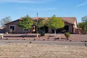 A single-story building with an American flag and trees in front.